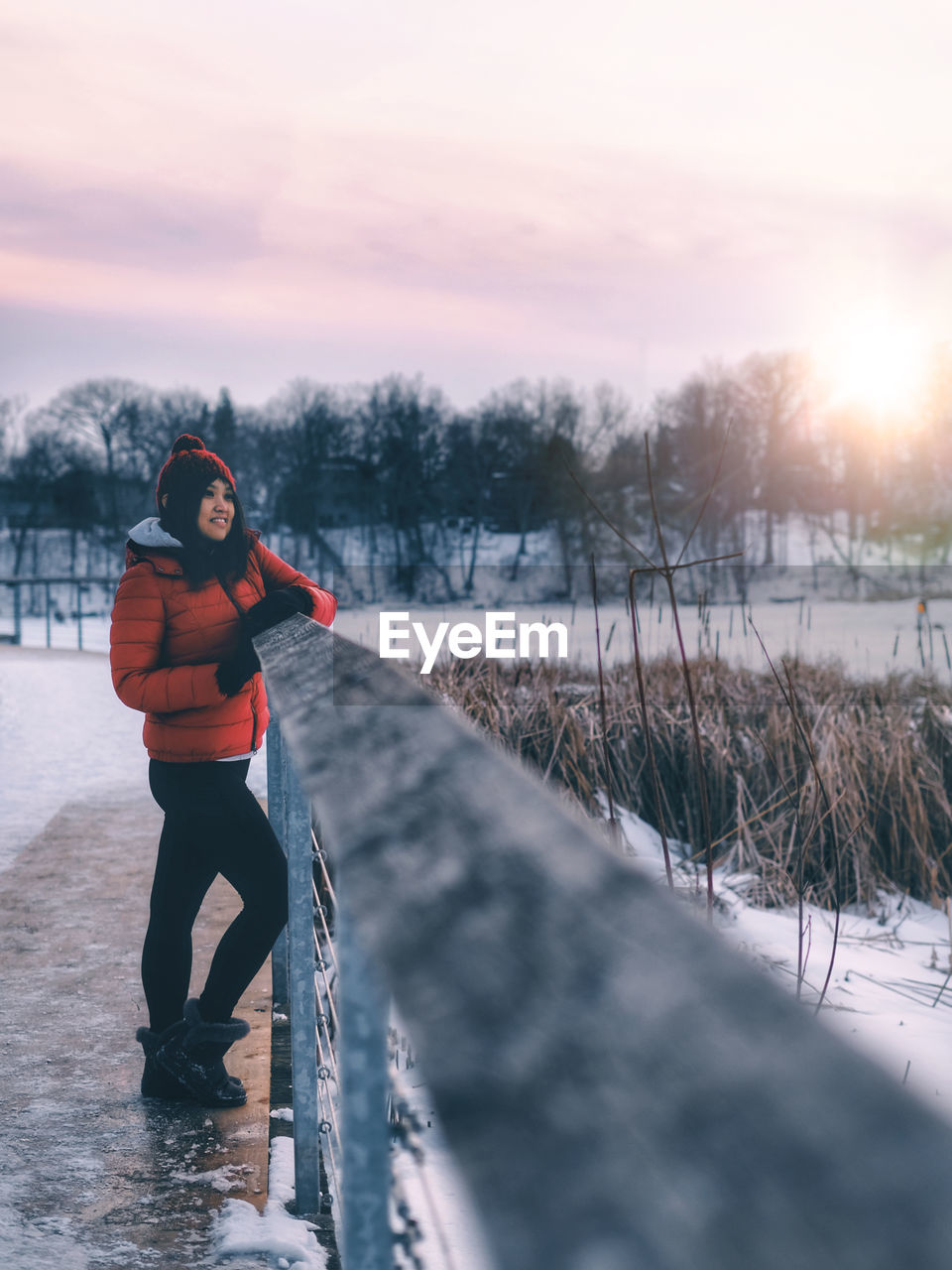 Woman standing in snow against sky during sunset