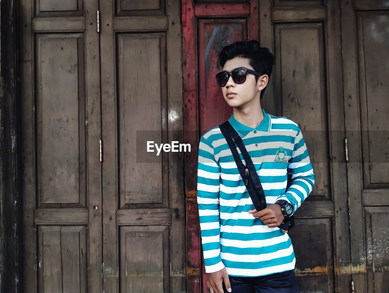 Full length of teenage boy wearing sunglasses standing against door