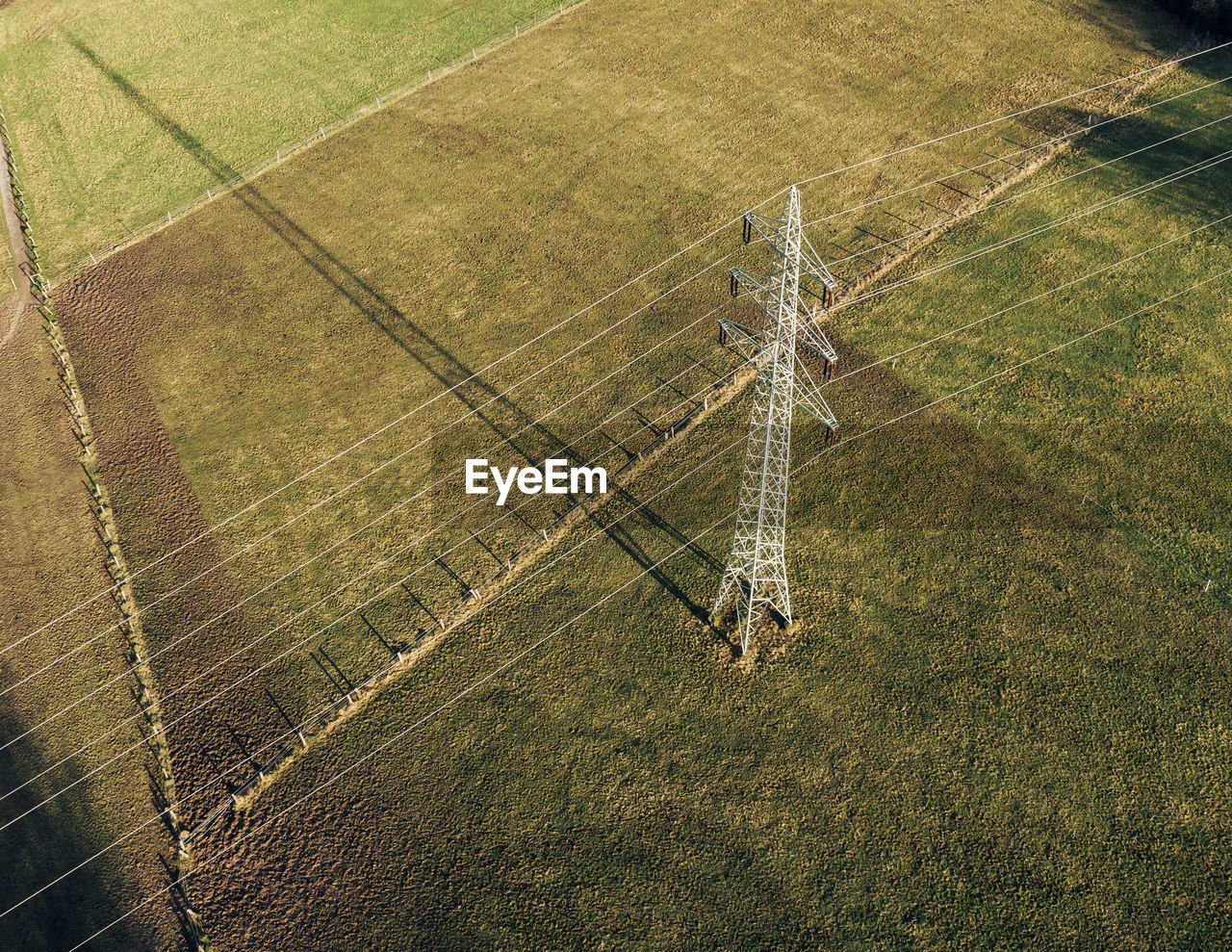 Power pole with strong shadow on a green field