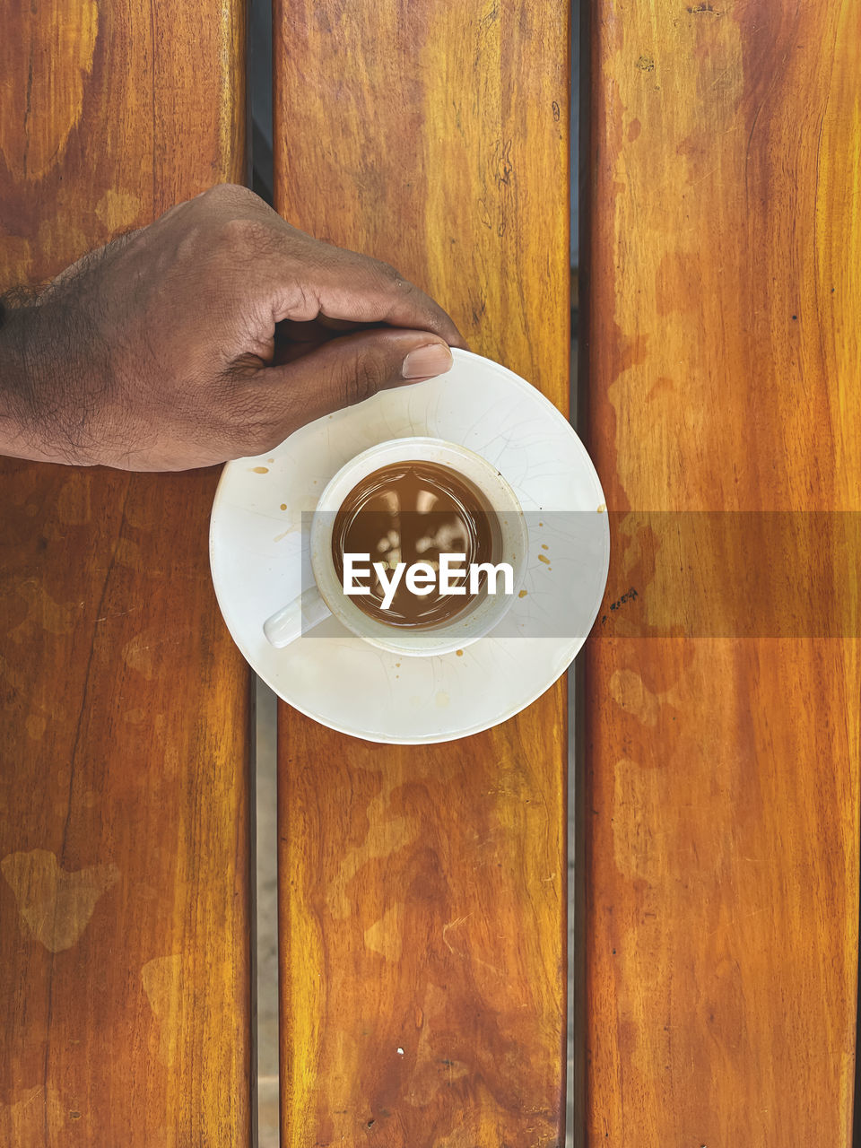 wood, food and drink, drink, hand, table, coffee, cup, refreshment, one person, coffee cup, mug, crockery, indoors, floor, food, adult, directly above, holding, brown, lifestyles, hardwood, wood stain, wood flooring, hot drink, saucer, close-up