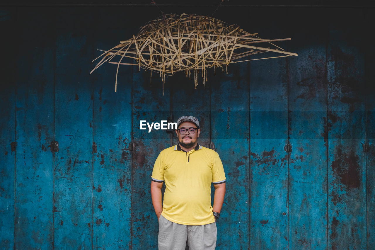 Portrait of man standing against wooden planks