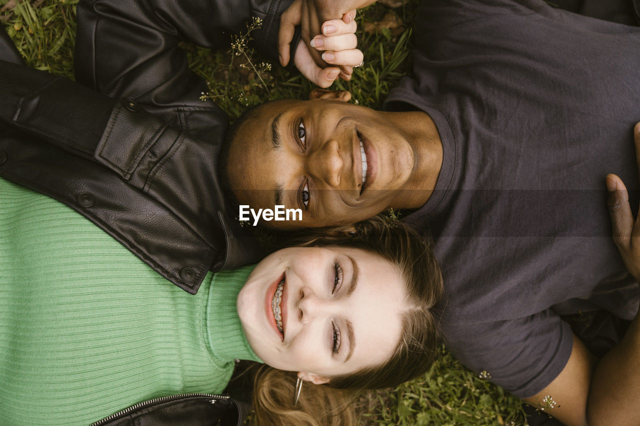 Directly above view of happy young woman and man lying on grass