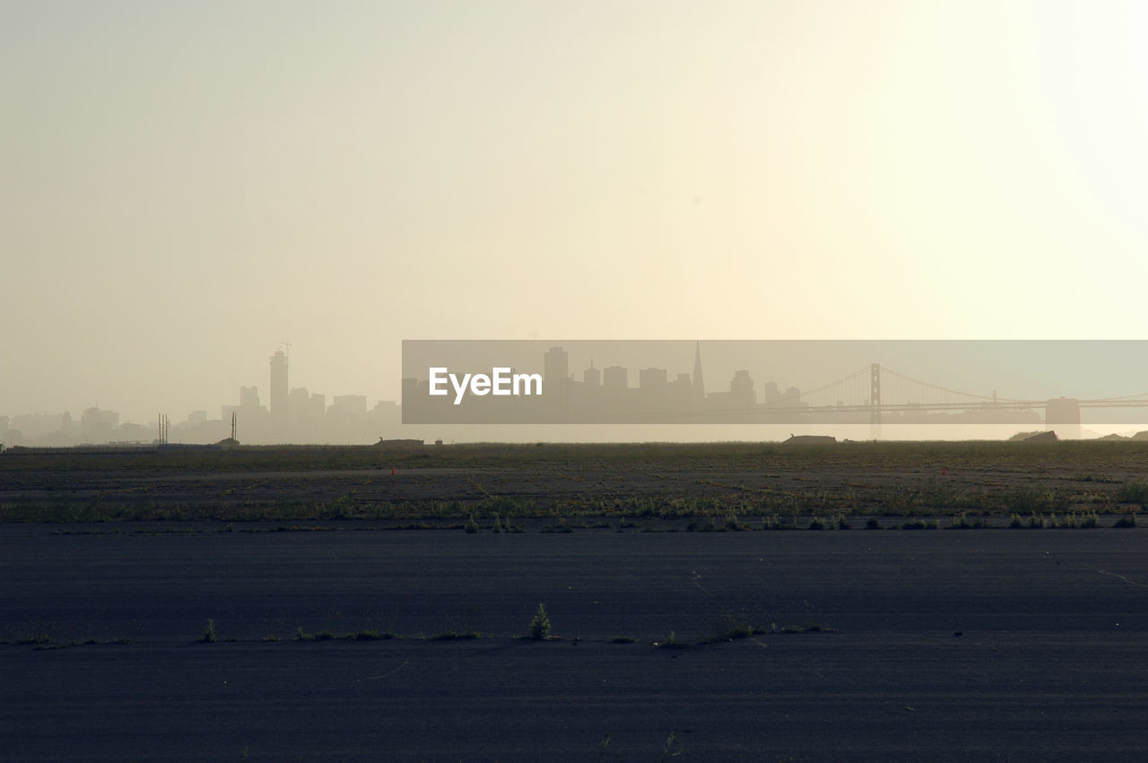 Scenic view of field against cityscape and sky