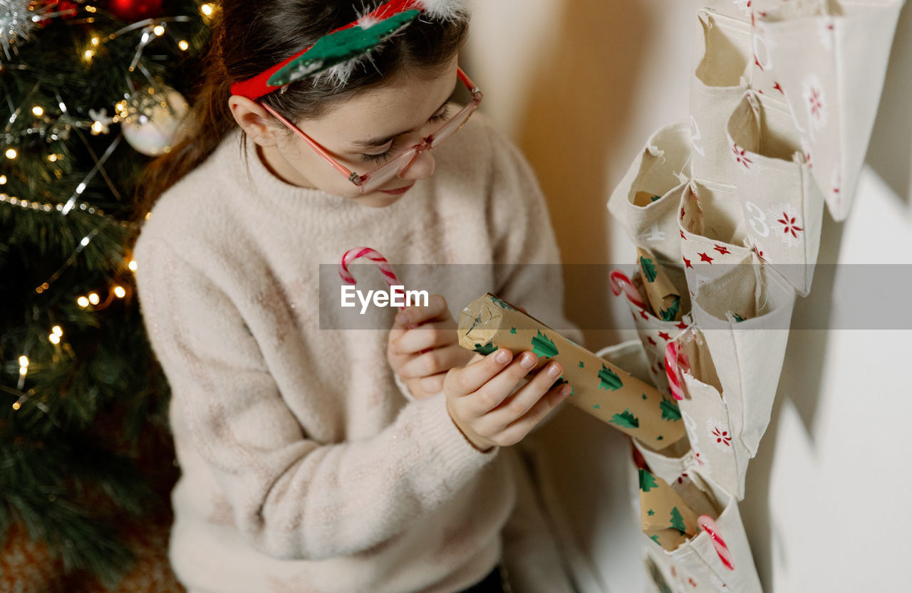 A girl takes out gifts from a wall advent calendar.