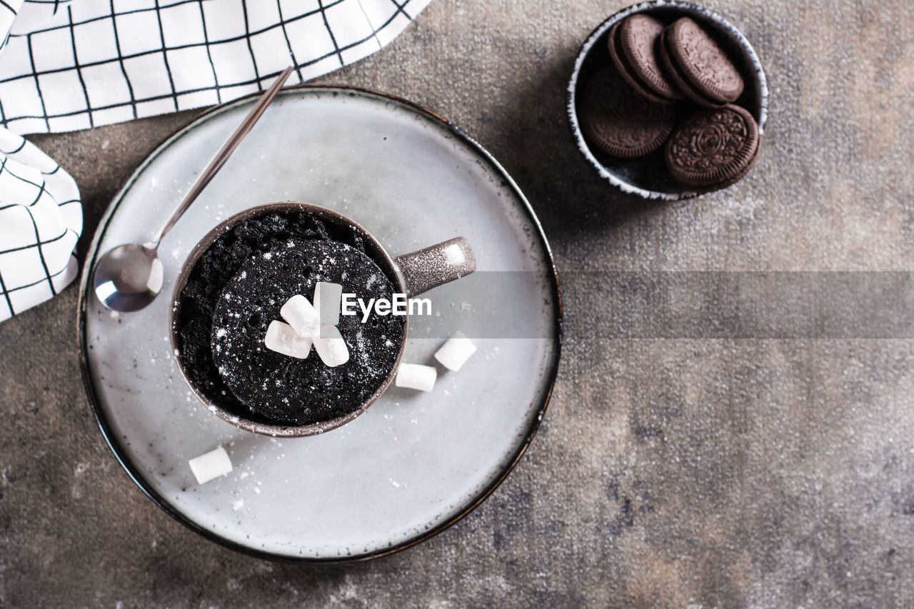 Chocolate cake in a mug with marshmallows and powdered sugar for homemade dessert top view