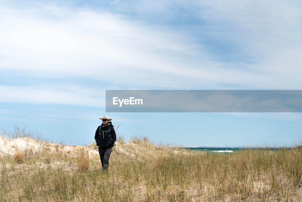 Man walking on field against sky