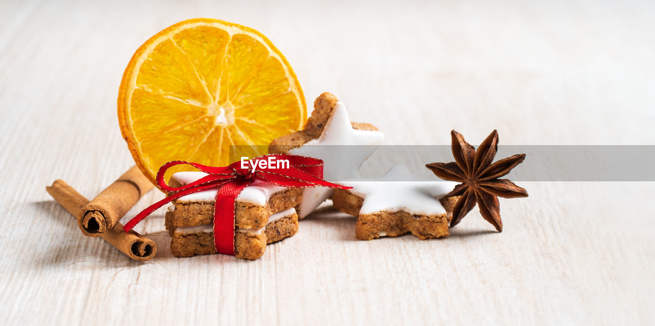 Traditional cinnamon cookies with orange on bright wooden planks.