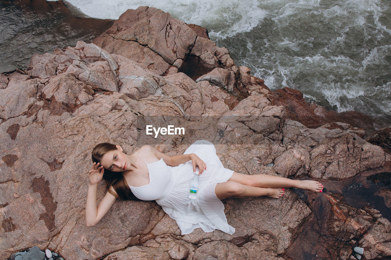 HIGH ANGLE VIEW OF WOMAN ON ROCKS