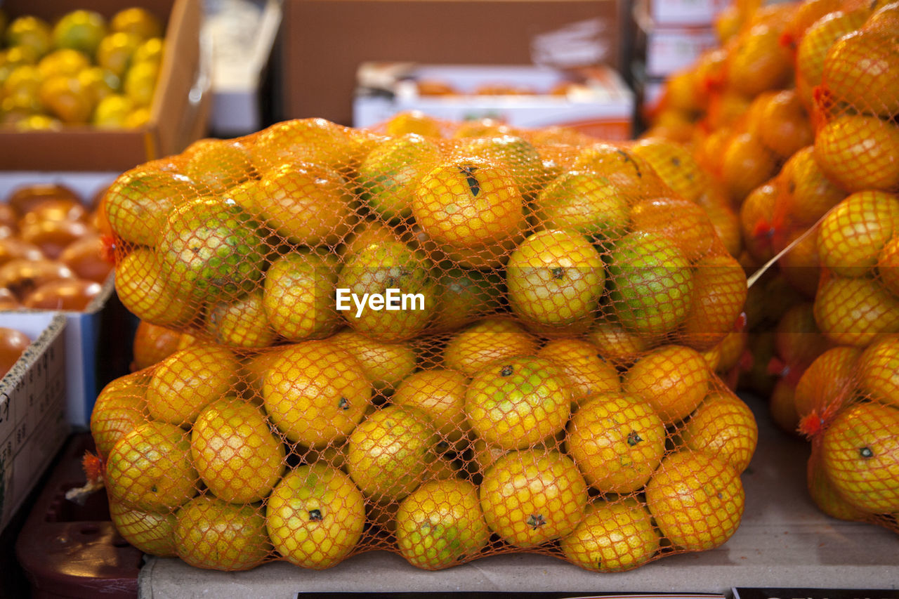 Close-up of tangerines in nets for sale at market stall