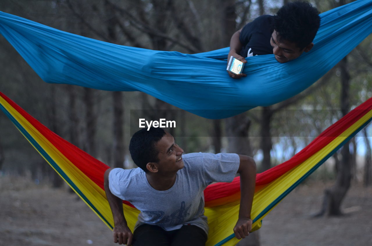 Playful men on hammocks in forest