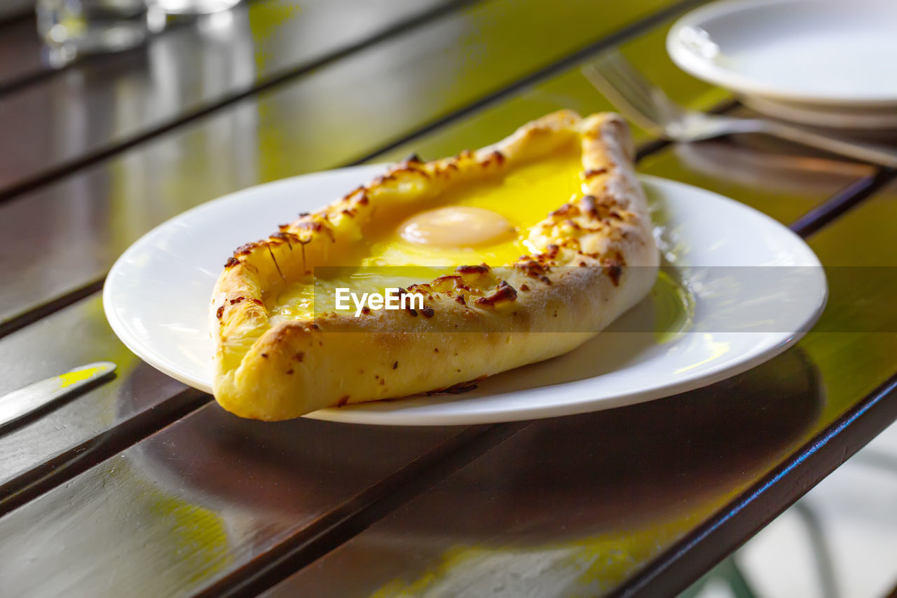 Adjara-style khachapuri, baked dough with egg, cheese and two pieces of butter 