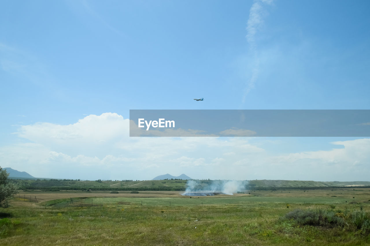 AIRPLANE FLYING OVER FIELD