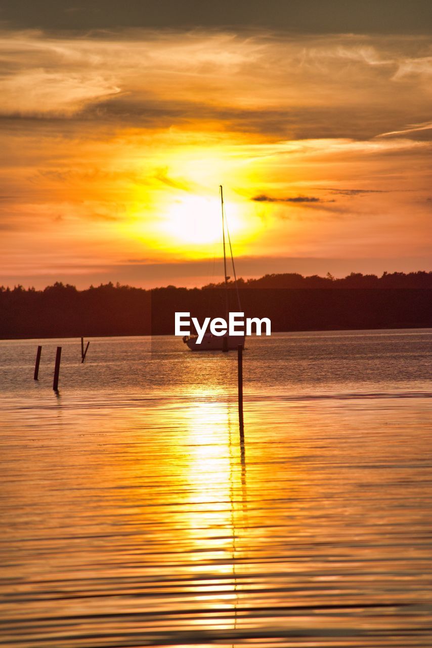 SILHOUETTE MAN IN SEA AGAINST ORANGE SKY