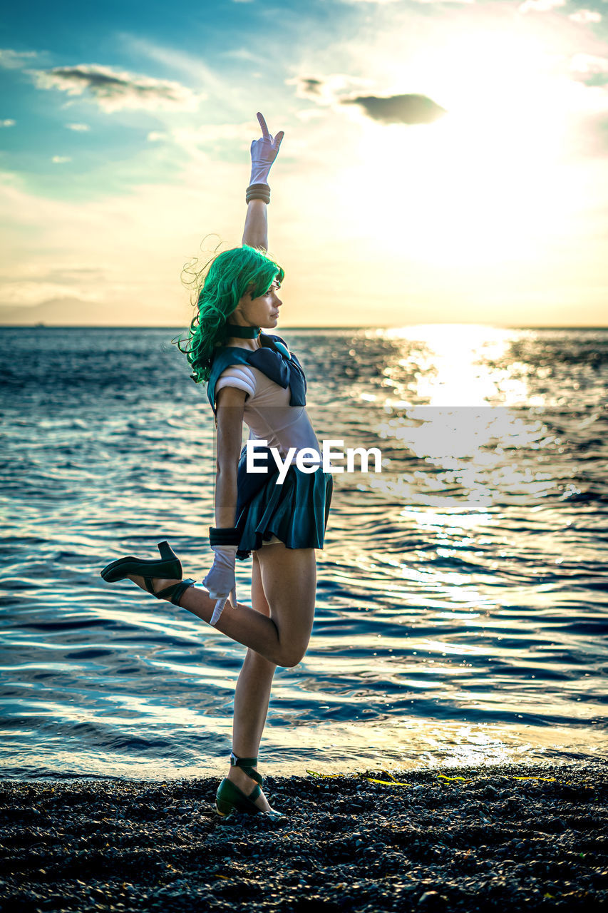 Full length of woman standing at beach against sky during sunset