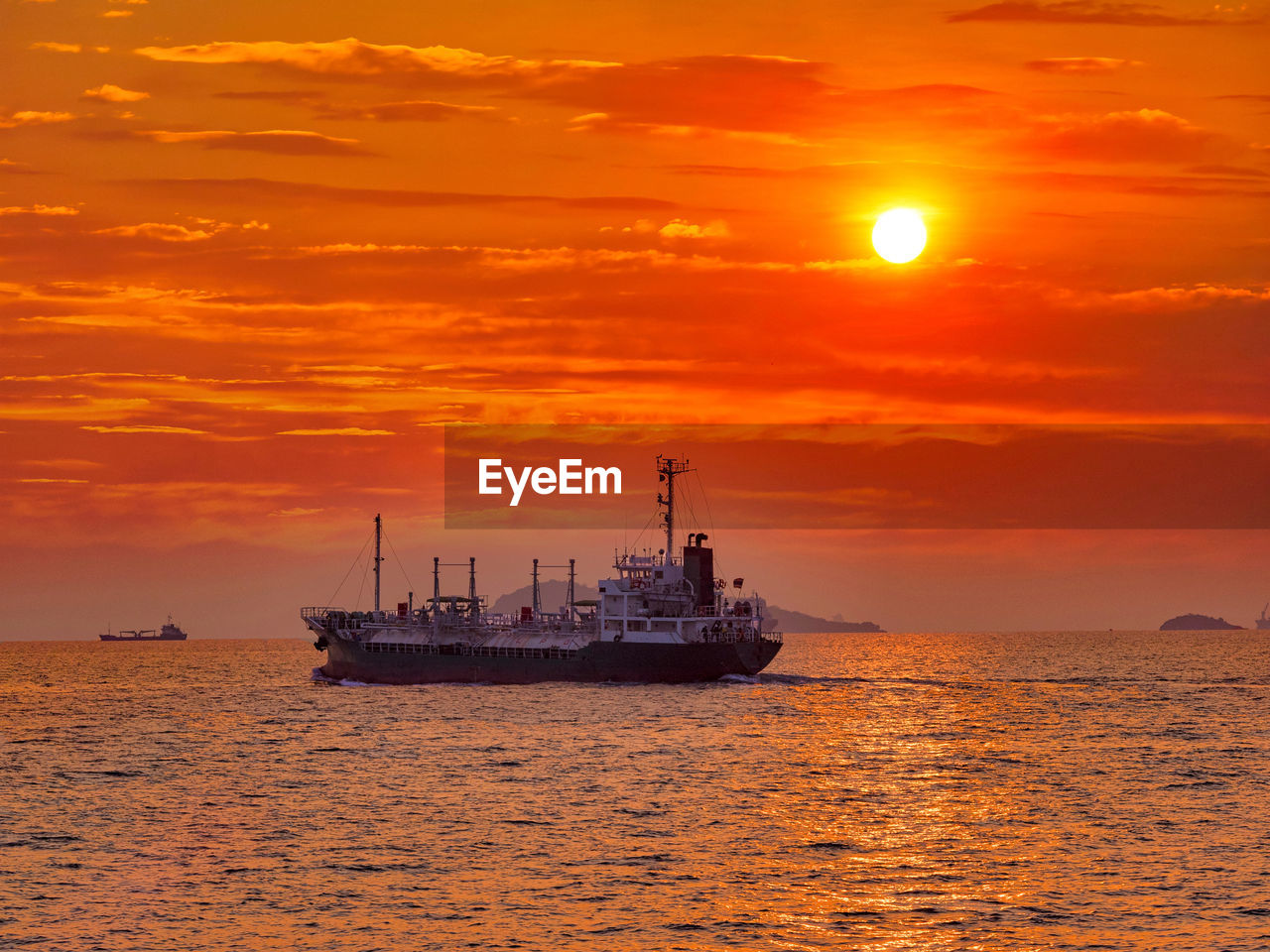 SHIP IN SEA AGAINST ORANGE SKY