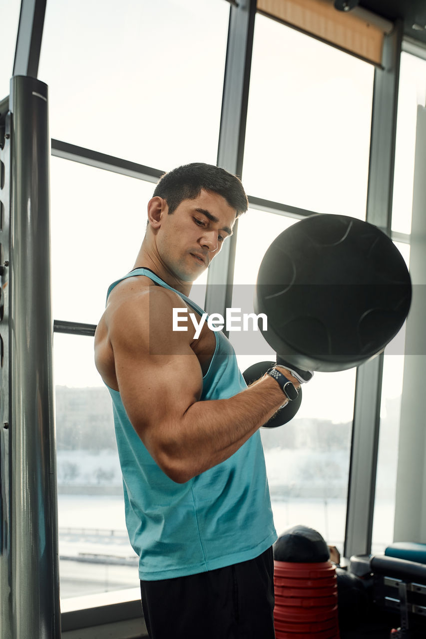 side view of shirtless man exercising in gym