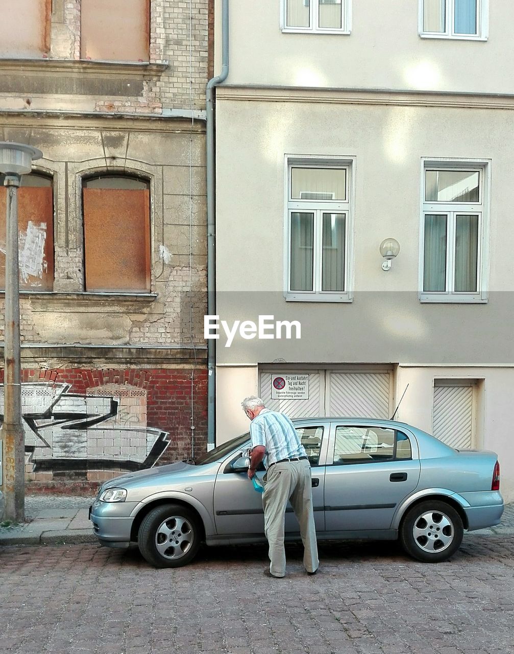 SIDE VIEW OF A MAN PARKED IN FRONT OF BUILDING