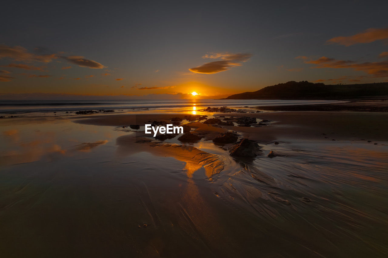 water, sky, sea, sunset, land, scenics - nature, beauty in nature, beach, nature, reflection, tranquility, ocean, cloud, tranquil scene, coast, sand, dawn, shore, horizon, environment, no people, sun, orange color, sunlight, landscape, horizon over water, seascape, travel destinations, wave, outdoors, travel, dramatic sky, evening, idyllic, non-urban scene, coastline, body of water