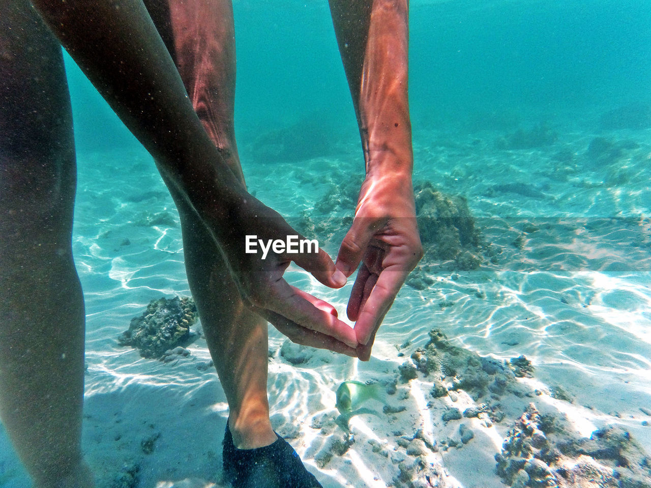 Cropped image of woman making heart shape in sea