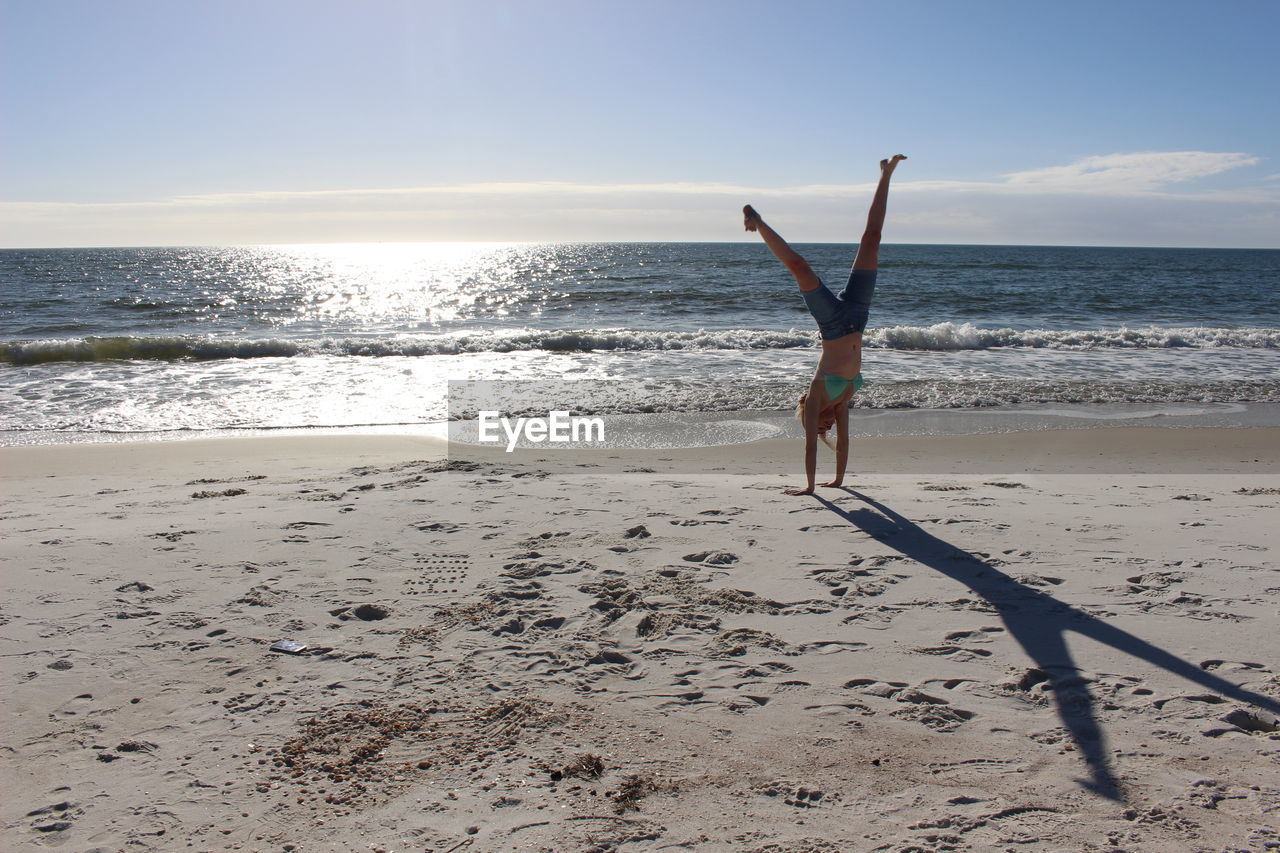 Woman doing cartwheel on sand at beach