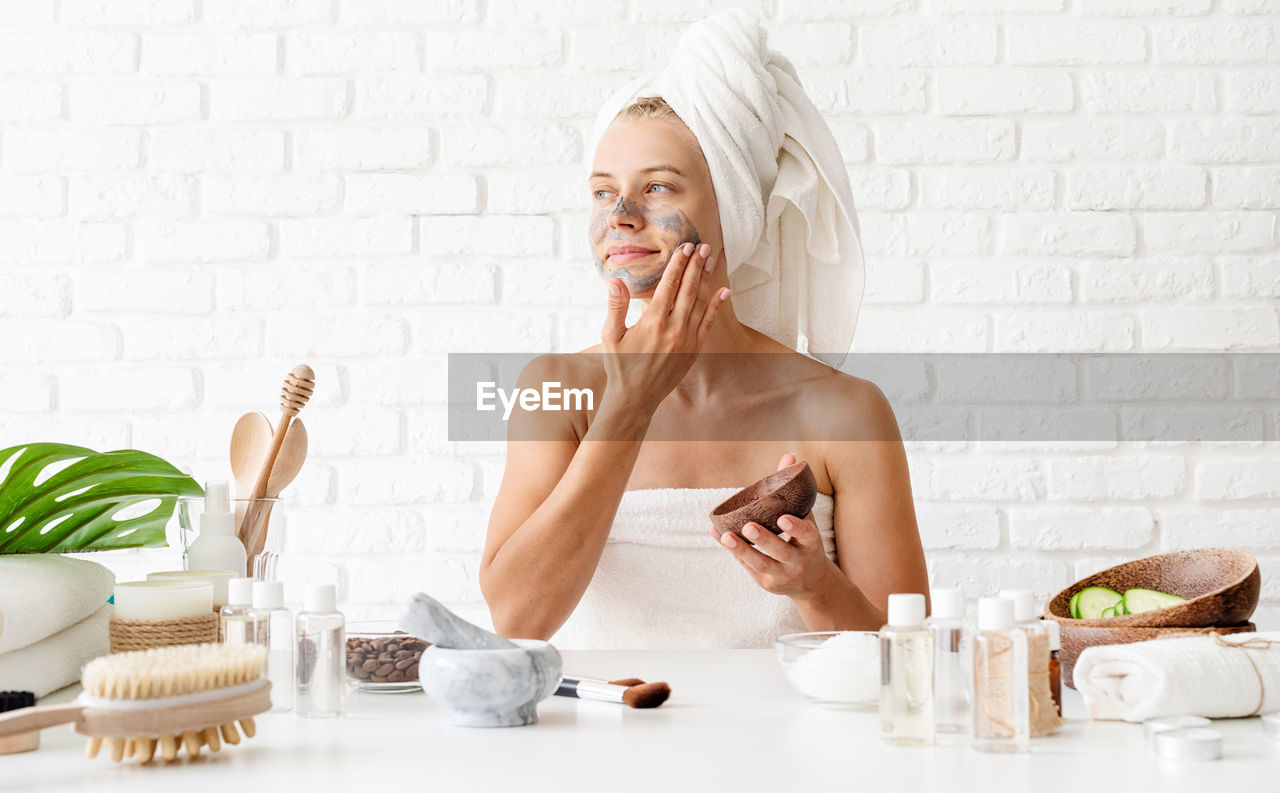 Spa and beauty. young woman wearing white towels applying spa facial mask on her face