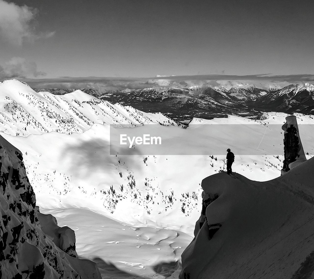 REAR VIEW OF MAN ON SNOWCAPPED MOUNTAINS