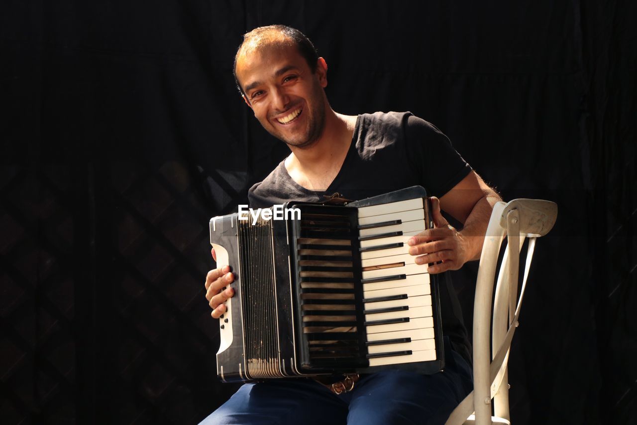 Portrait of smiling musician playing accordion on stage