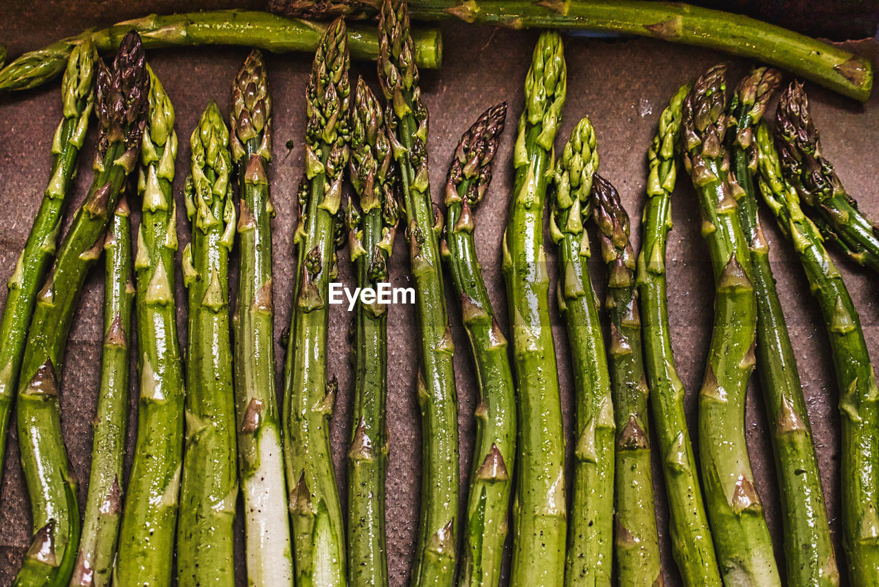 Asparagus shoots in row lying on paper. high angle view.