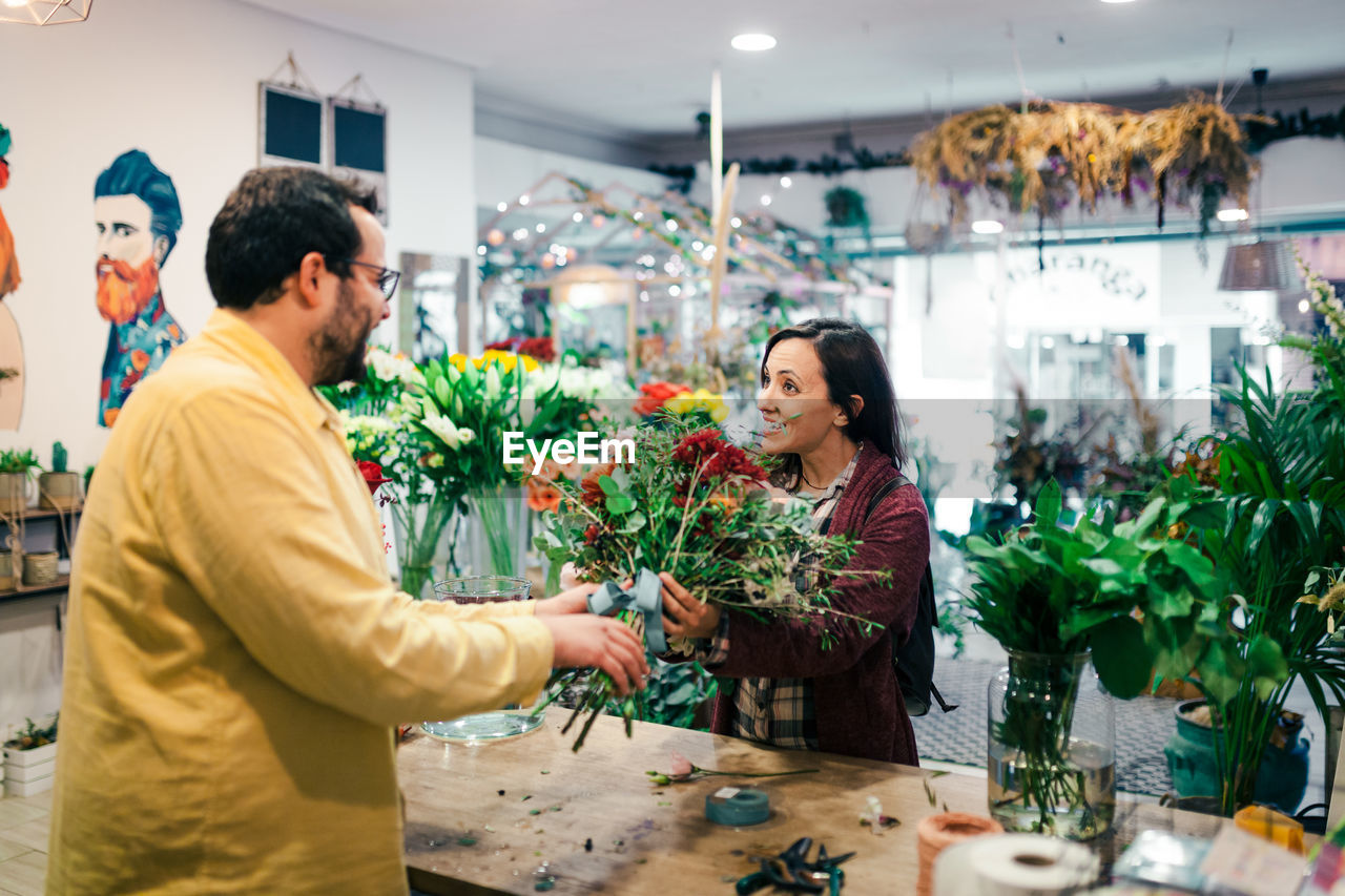 Man holding bouquet talking with women at store