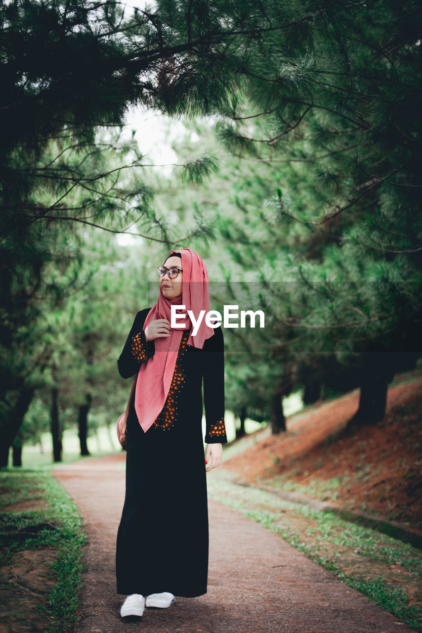 Woman looking up while walking against in park