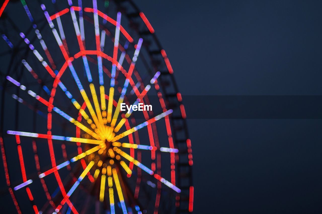 Illuminated defocused ferris wheel at night