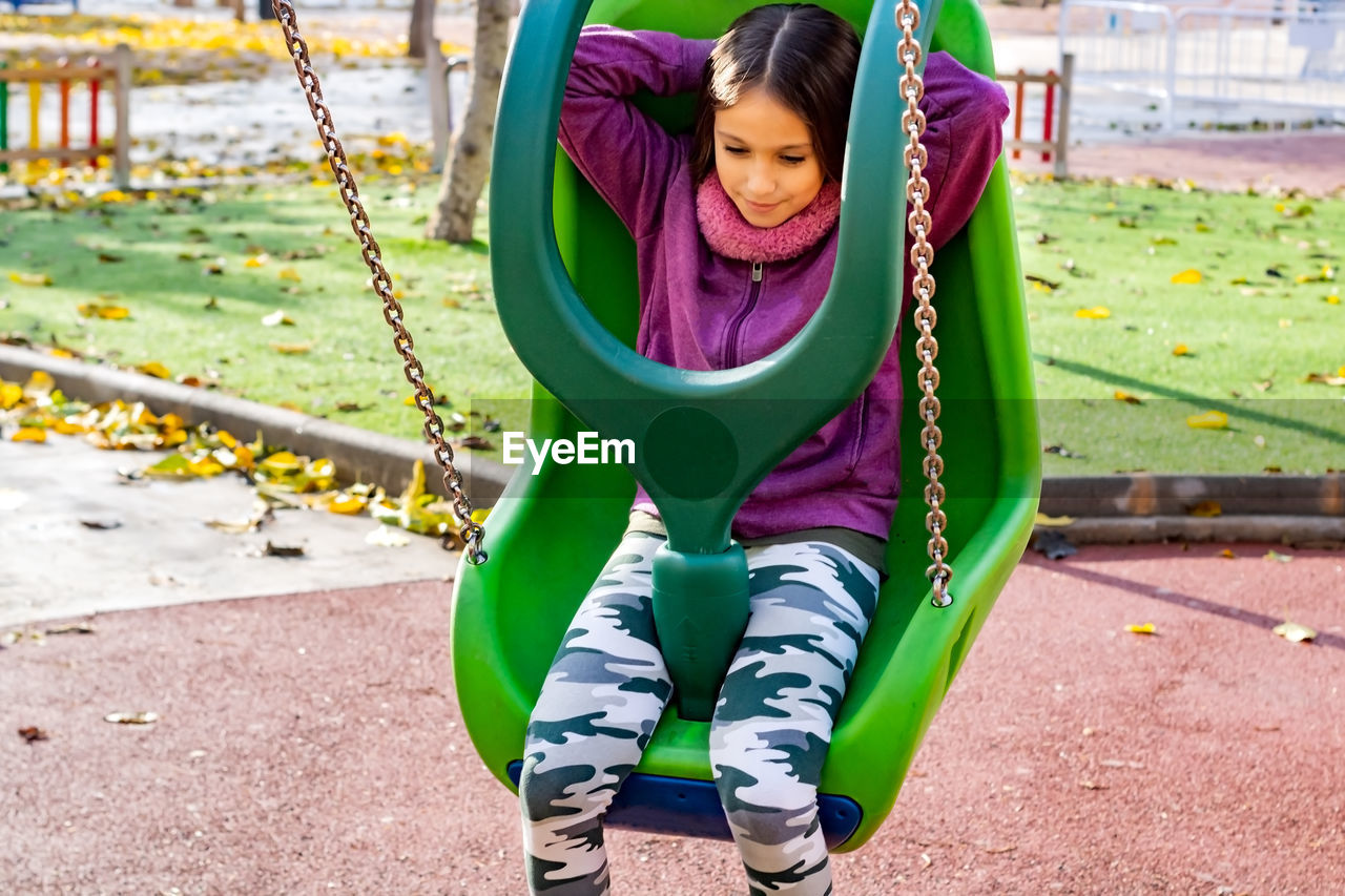 Girl playing on swing at playground