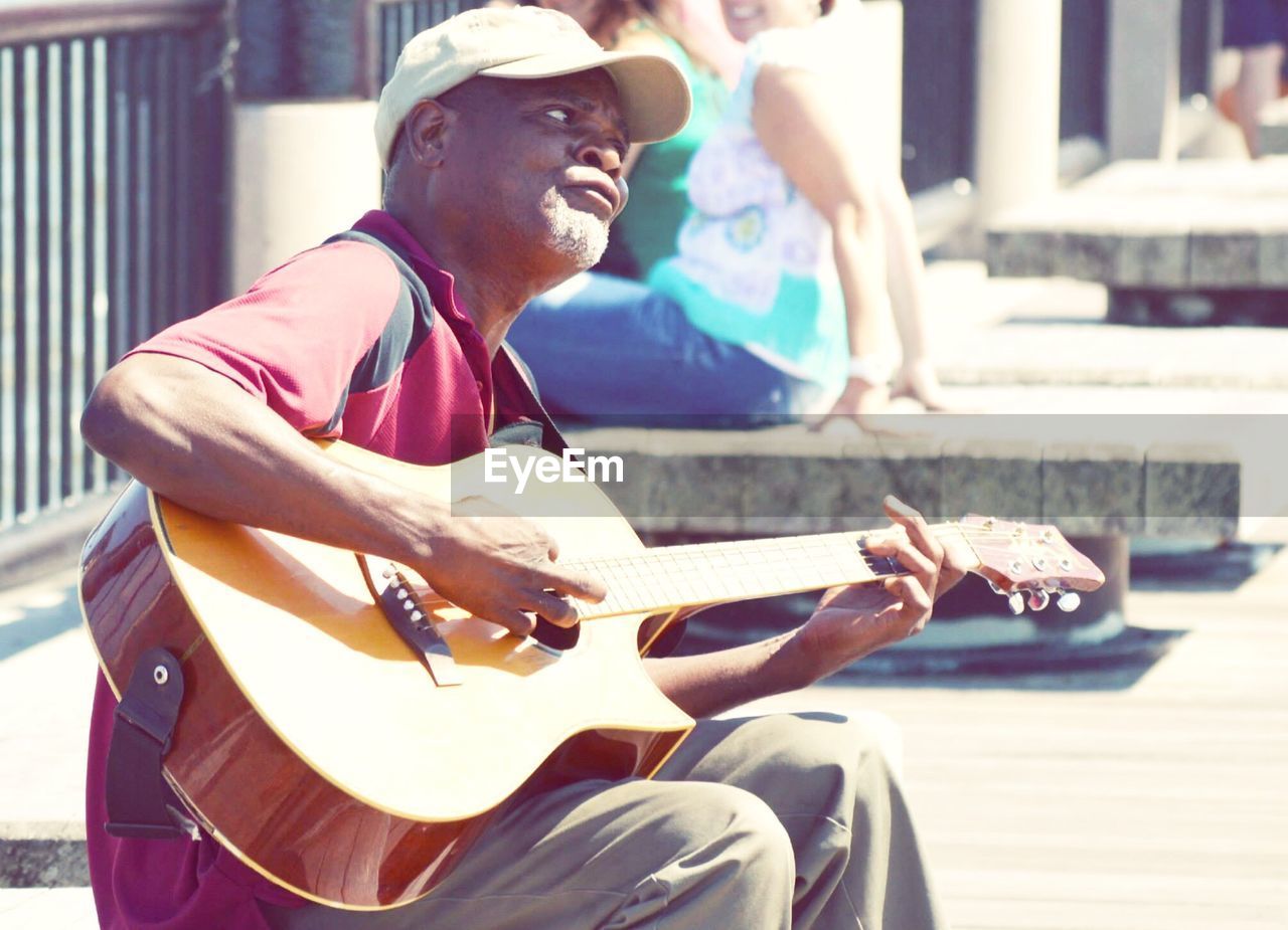 Street musician playing guitar on sunny day