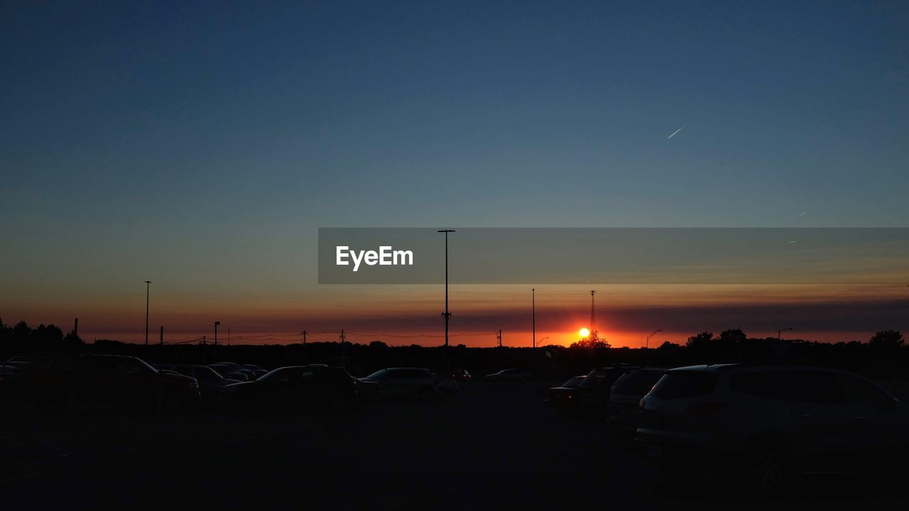 CARS ON ROAD AGAINST SKY AT SUNSET