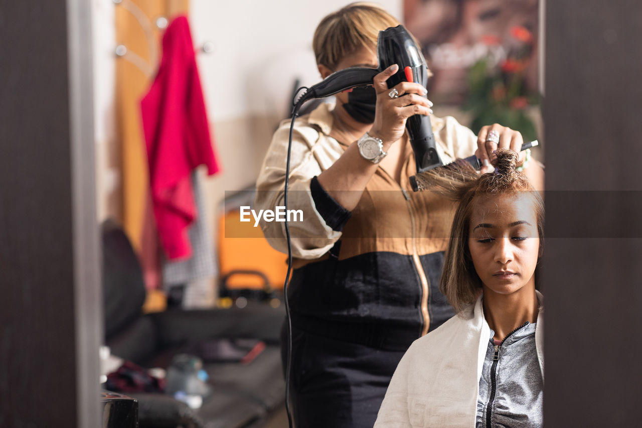 Hairdresser styling customers hair at salon