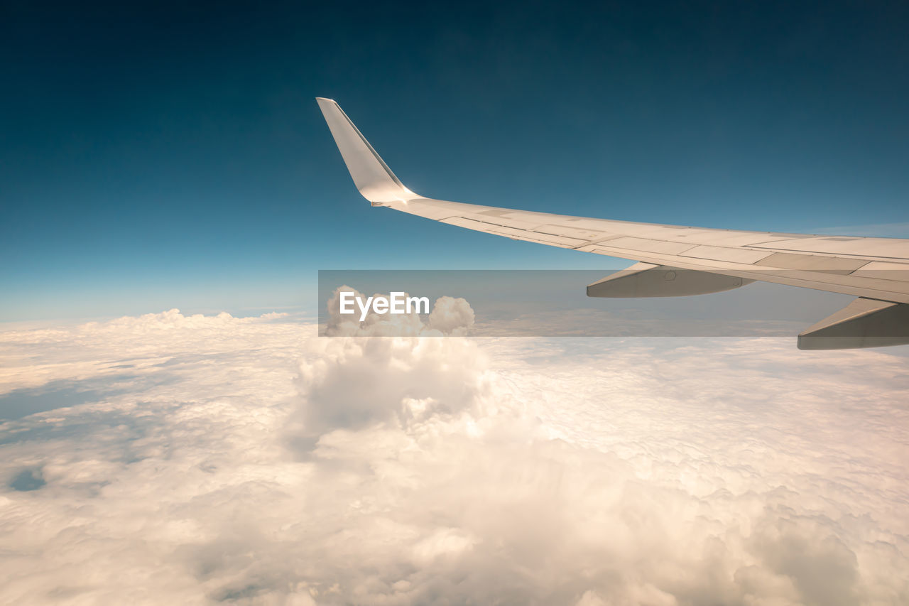 Airplane flying above the clouds at sunset.