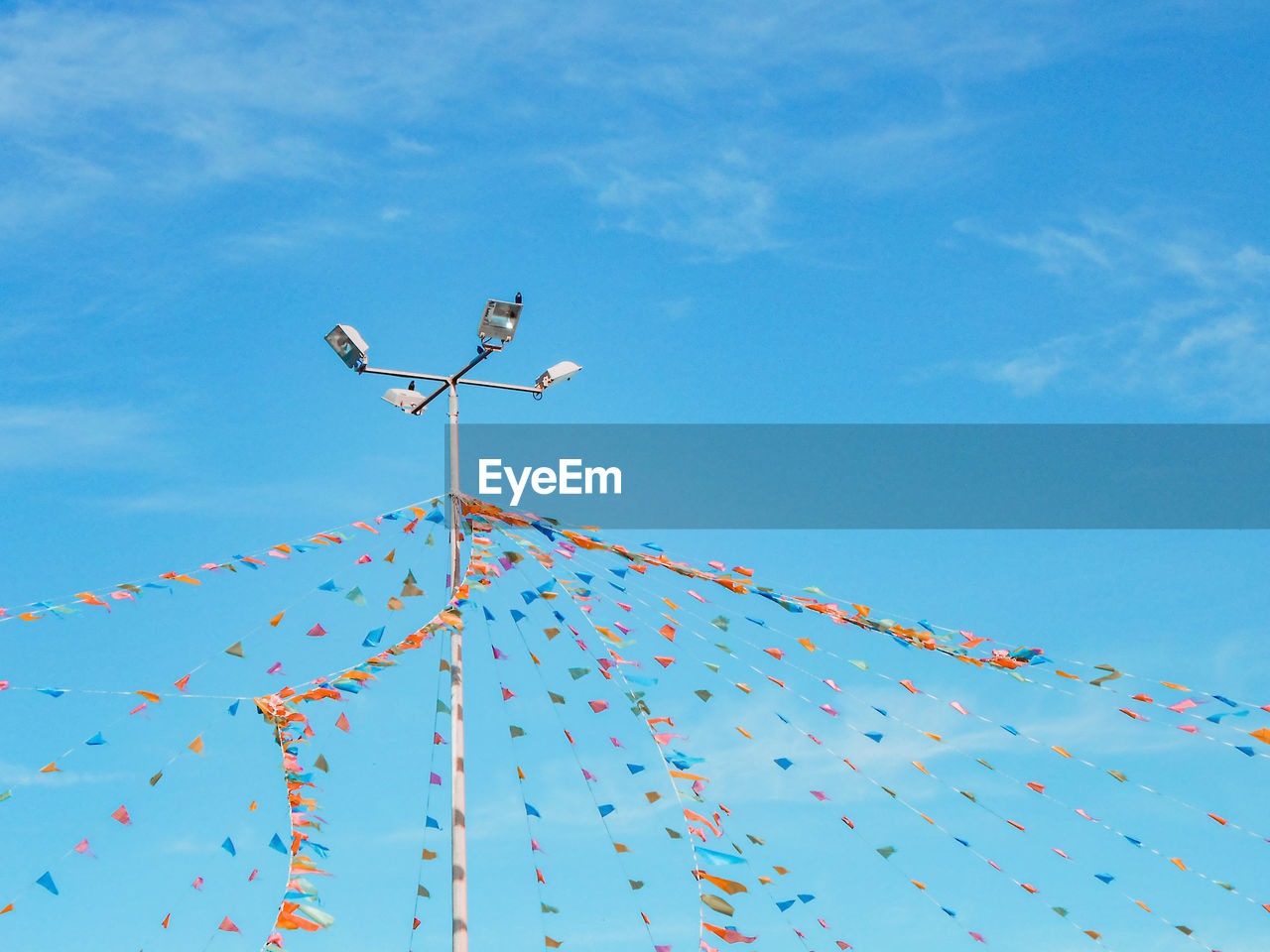 Low angle view of pole and bunting against blue sky