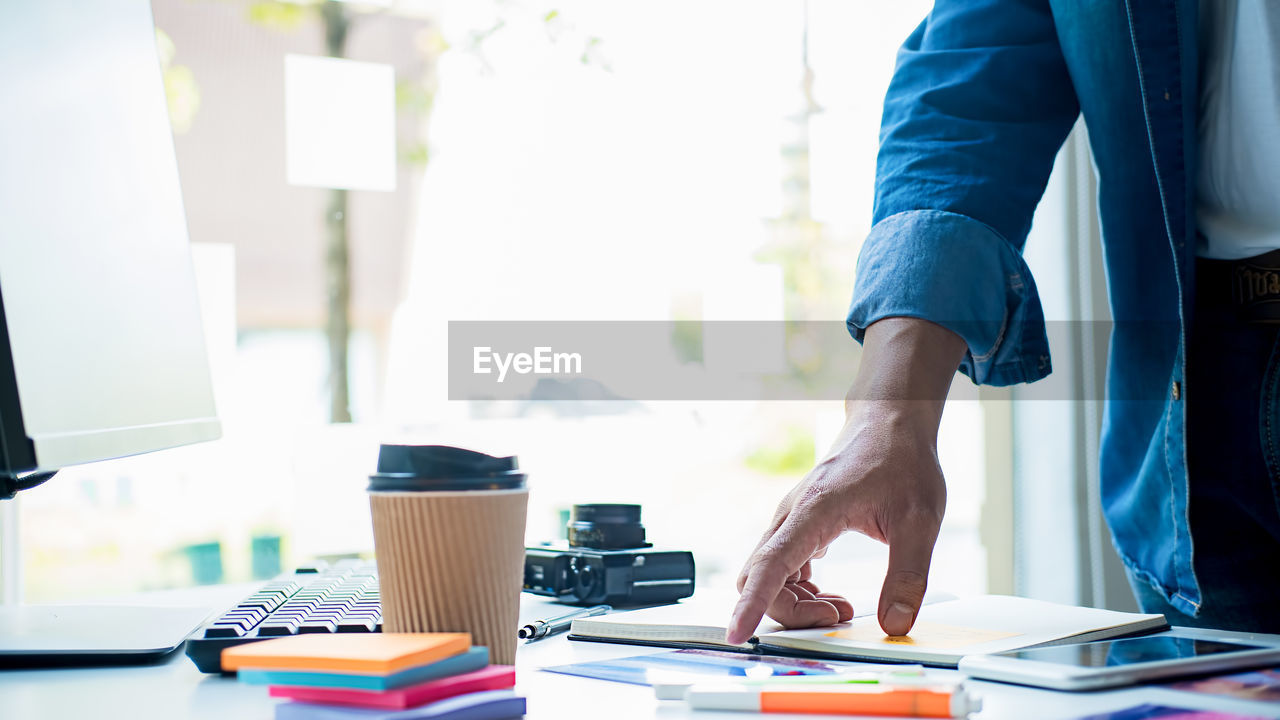 Midsection of businessman standing at desk in office