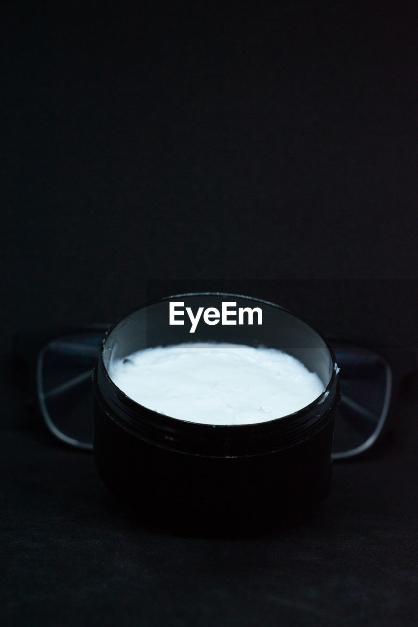 CLOSE-UP OF COFFEE CUP AGAINST BLACK BACKGROUND