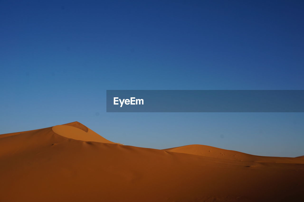 SCENIC VIEW OF SAND DUNES AGAINST CLEAR BLUE SKY