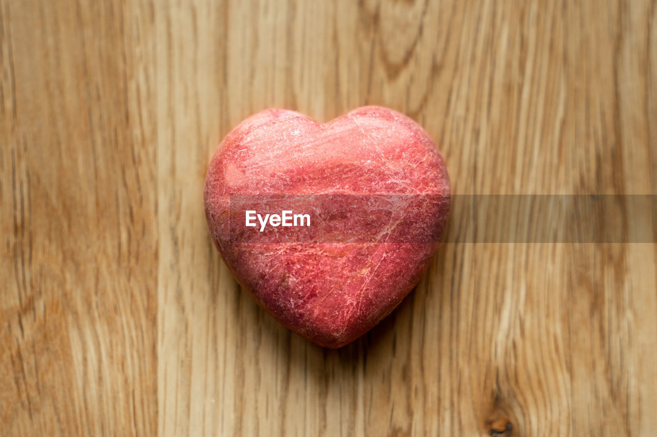 Stone heart on wooden background with natural light