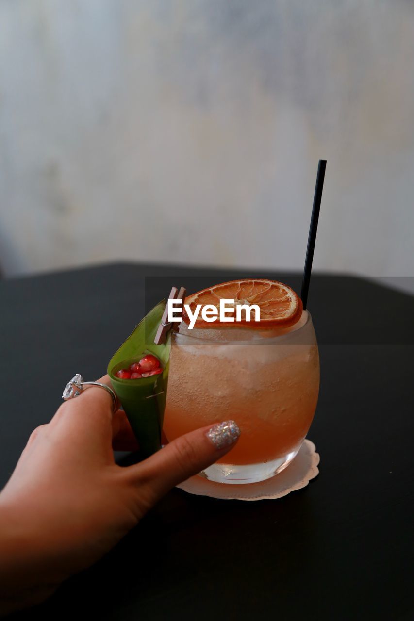 Cropped hand holding drink on table