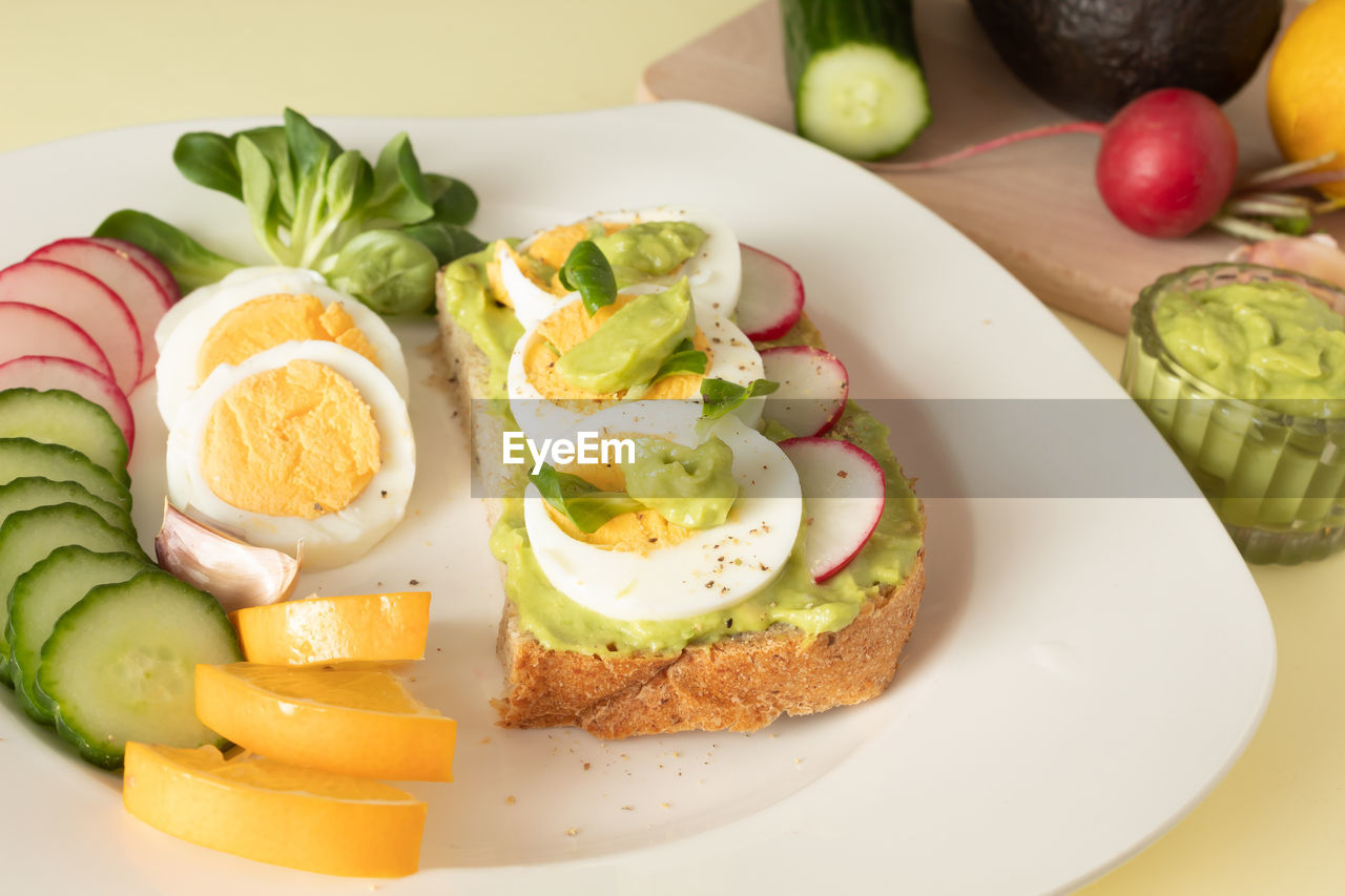 Avocado toast with guacamole, cucumber, radish and sliced boiled egg. ingredients for avocado salad. 