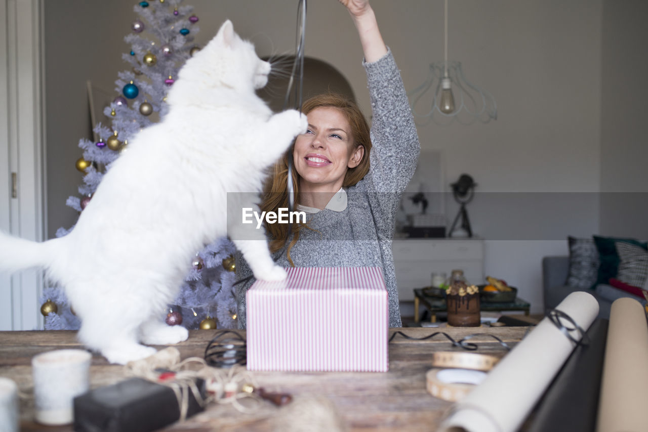 Woman playing with cat while packing present