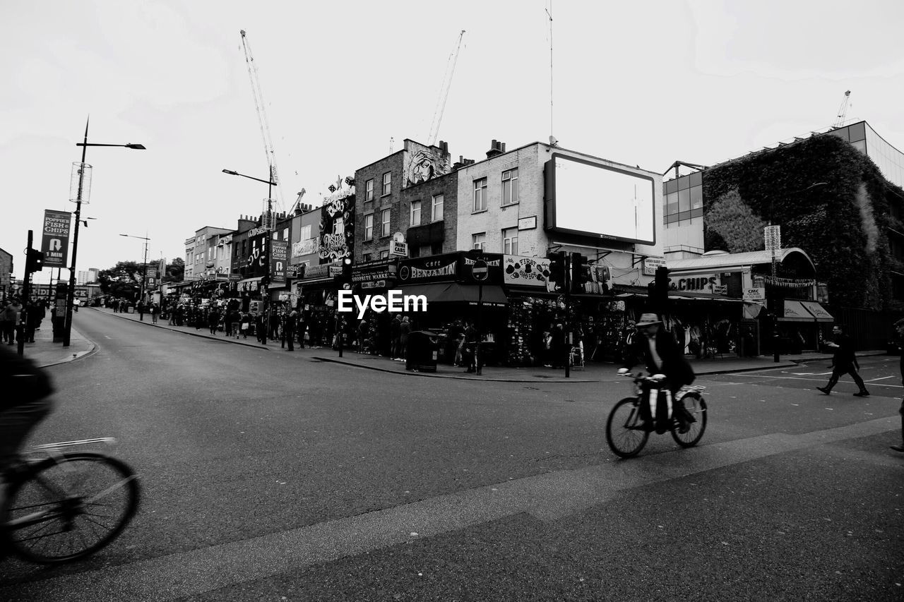 MAN RIDING BICYCLE ON ROAD AGAINST SKY