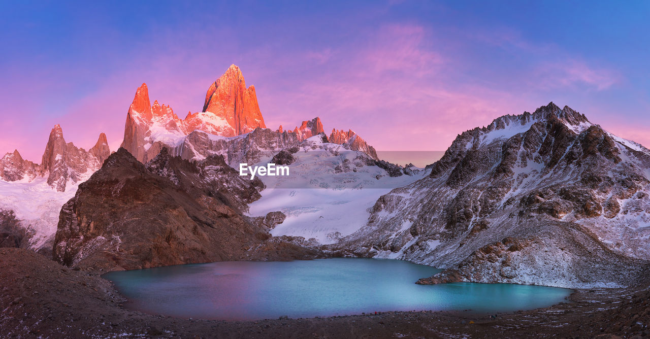 Scenic view of lake and snowcapped mountains against sky during sunset
