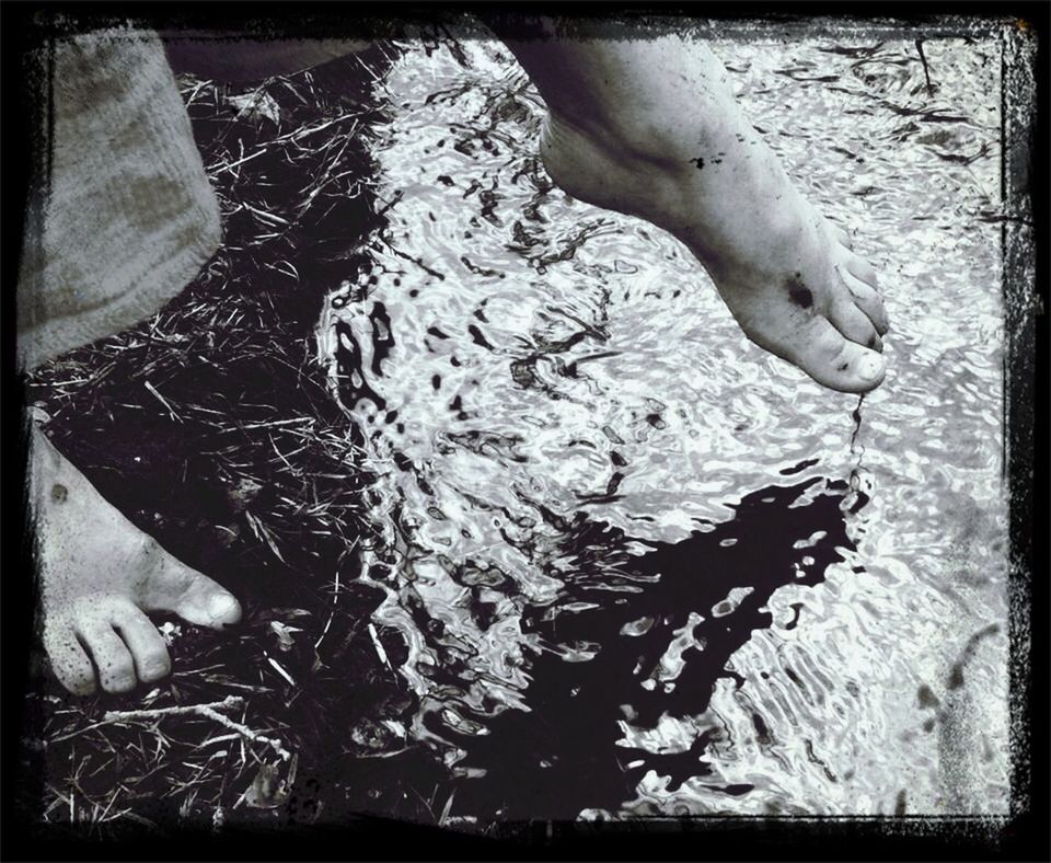 Close-up low section of bare feet in water