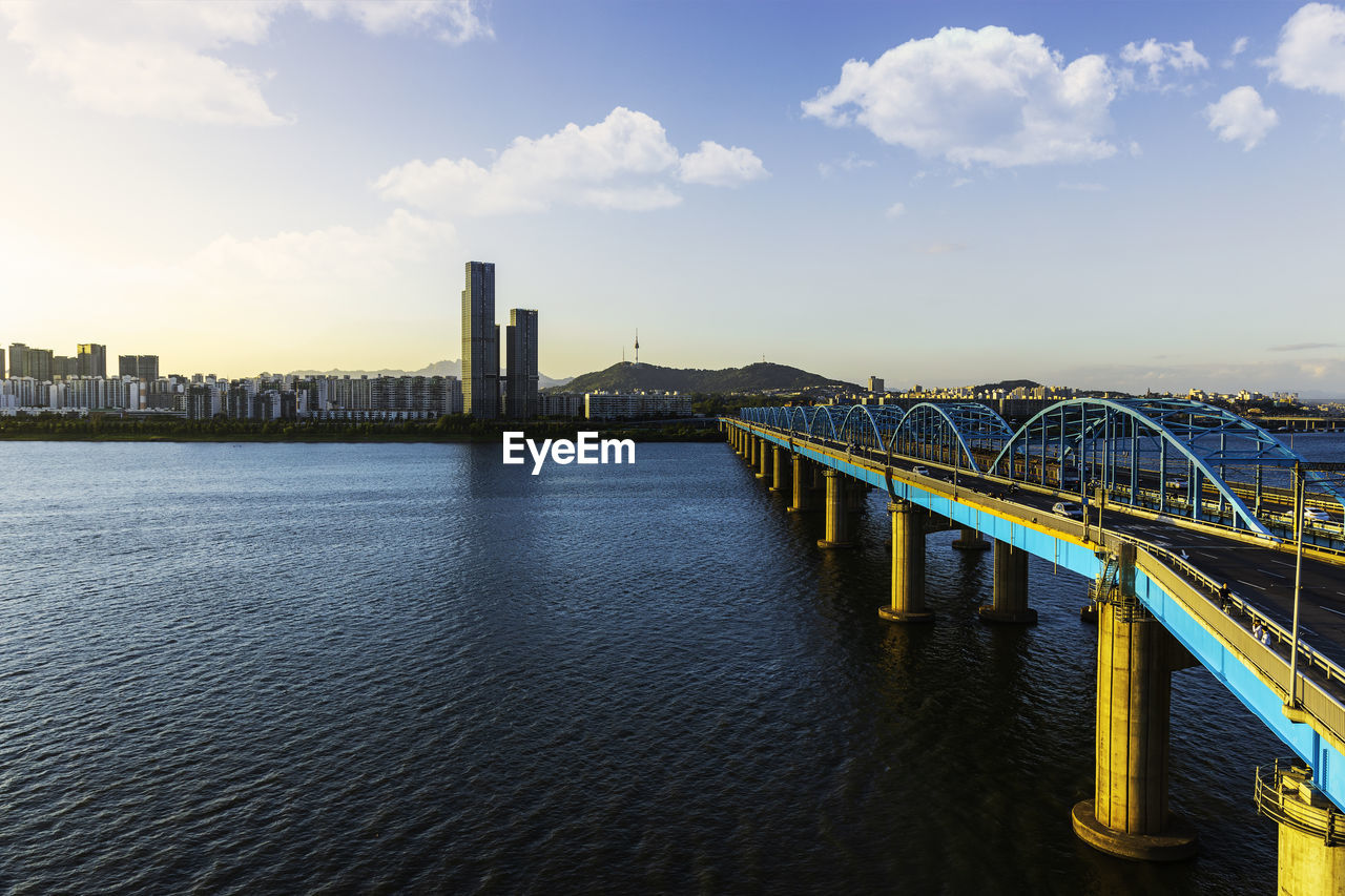 Bridge over river against sky in city