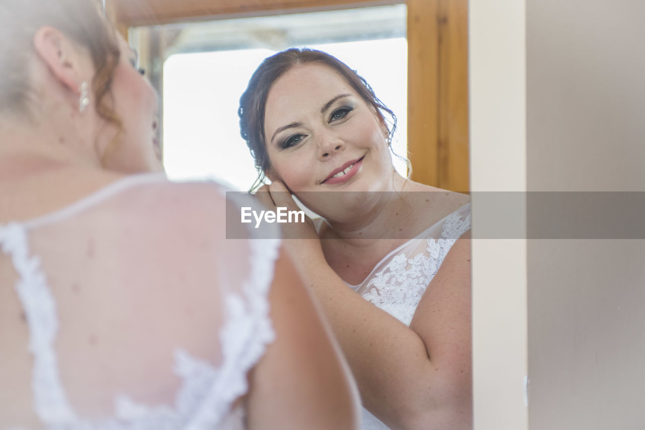 Reflection of smiling woman in mirror at home