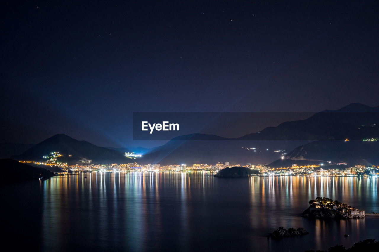 Scenic view of illuminated sea against sky at night